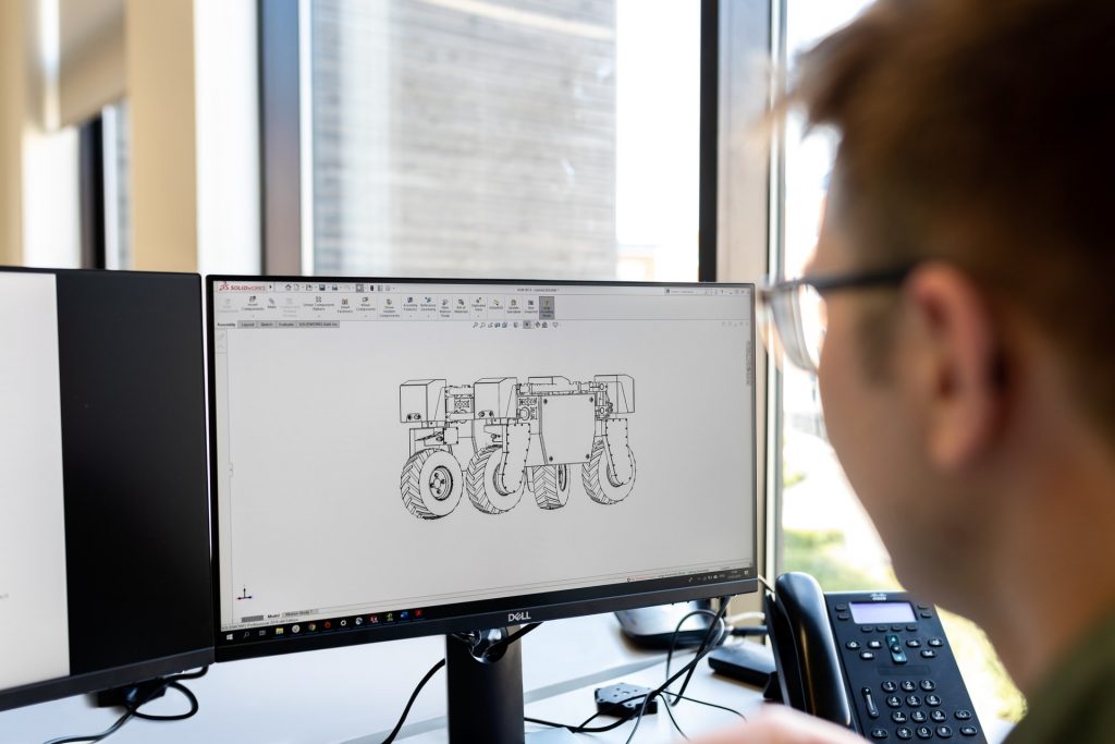 Mann sitzt vor Bildschirm mit CAD Konstruktionszeichnung auf Laptop Bildschirm